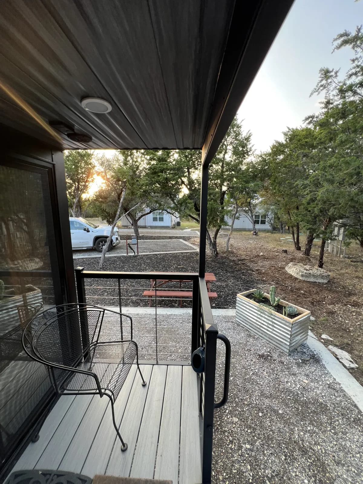 Covered deck at Blancobreeze with the sun setting through the trees