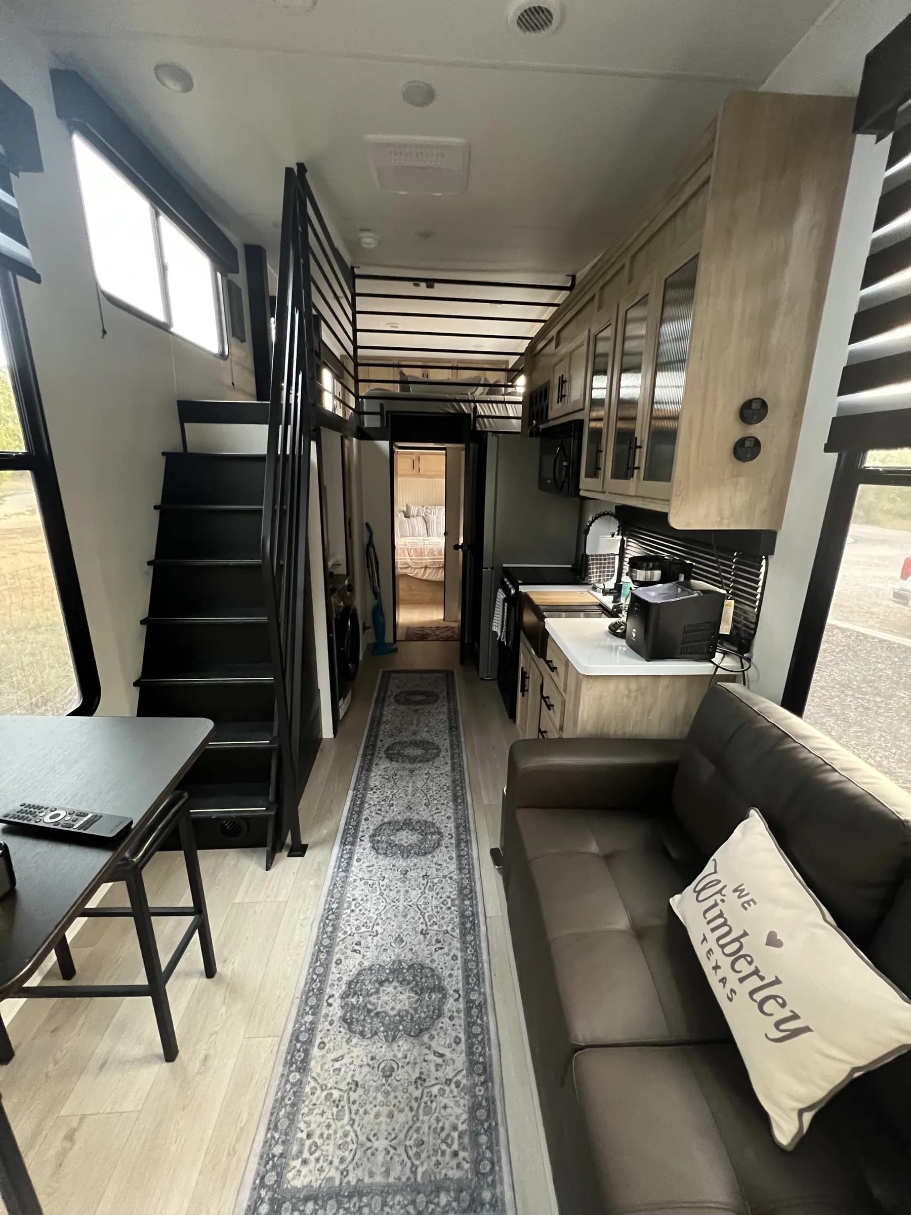 Blancobreeze interior with lounge seating, kitchen, and loft stairs