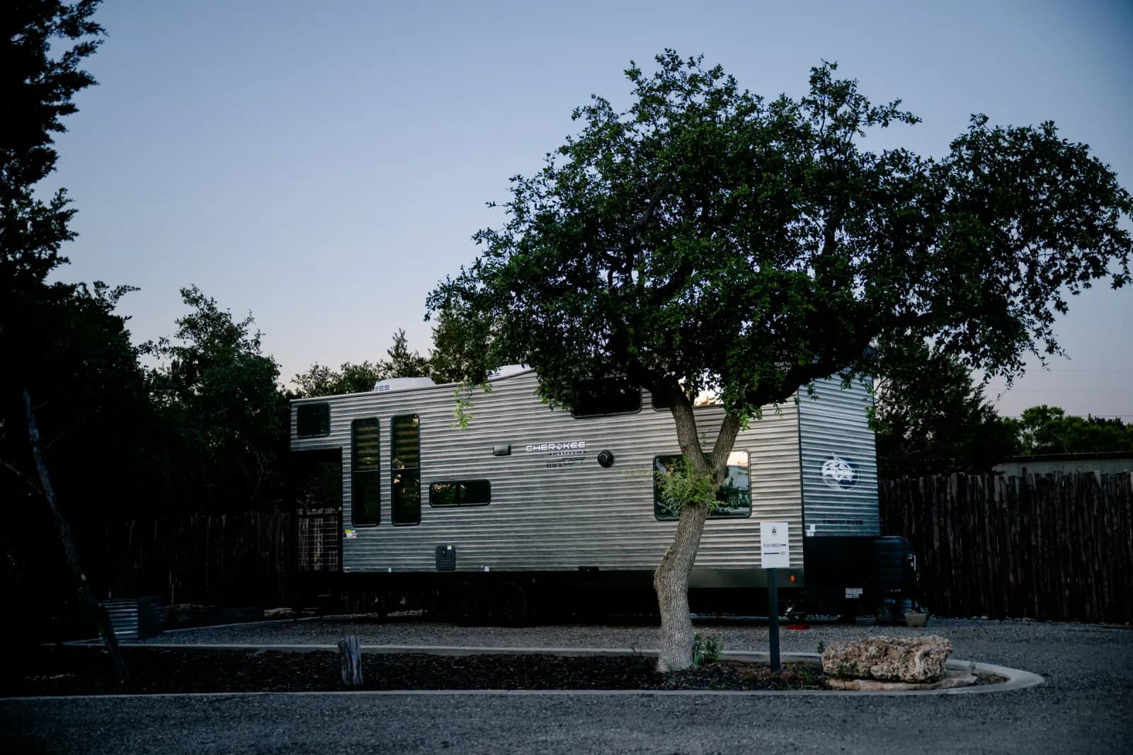 Blancobreeze glamping RV under a live oak at dusk at Wayside Wimberley