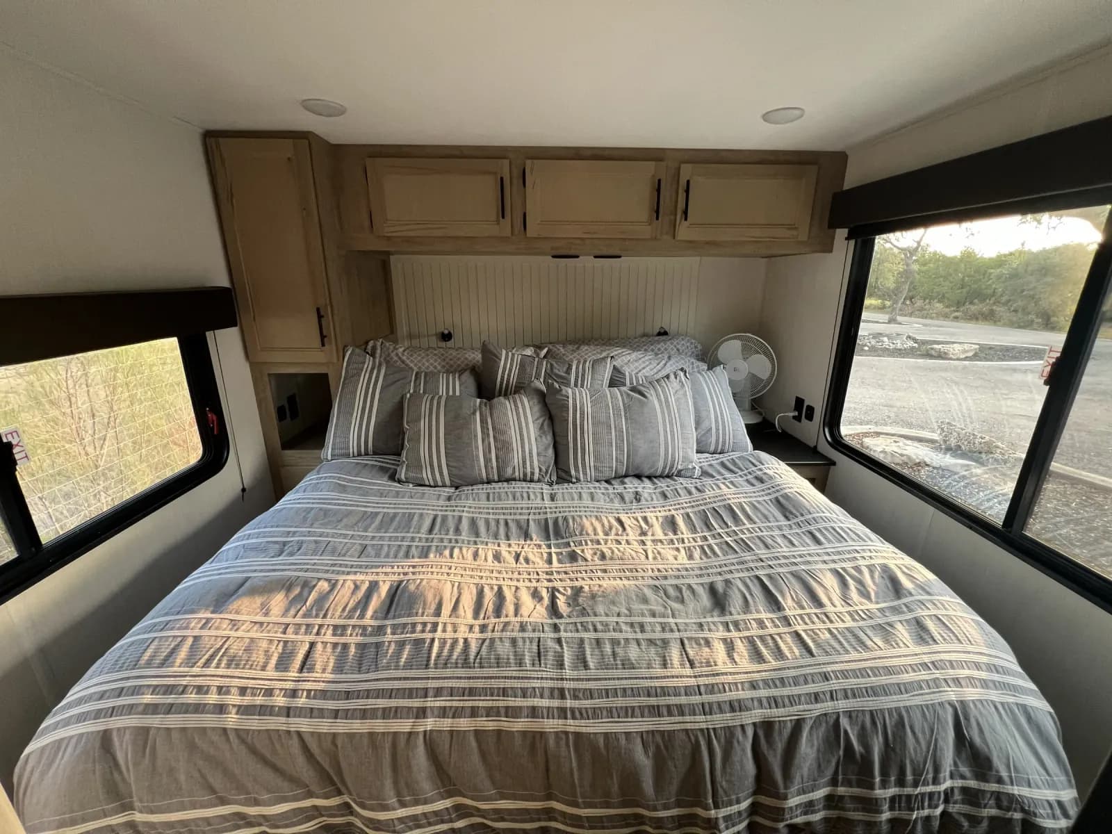 Bedroom with striped bedding, wood cabinets, and large windows inside Blancobreeze