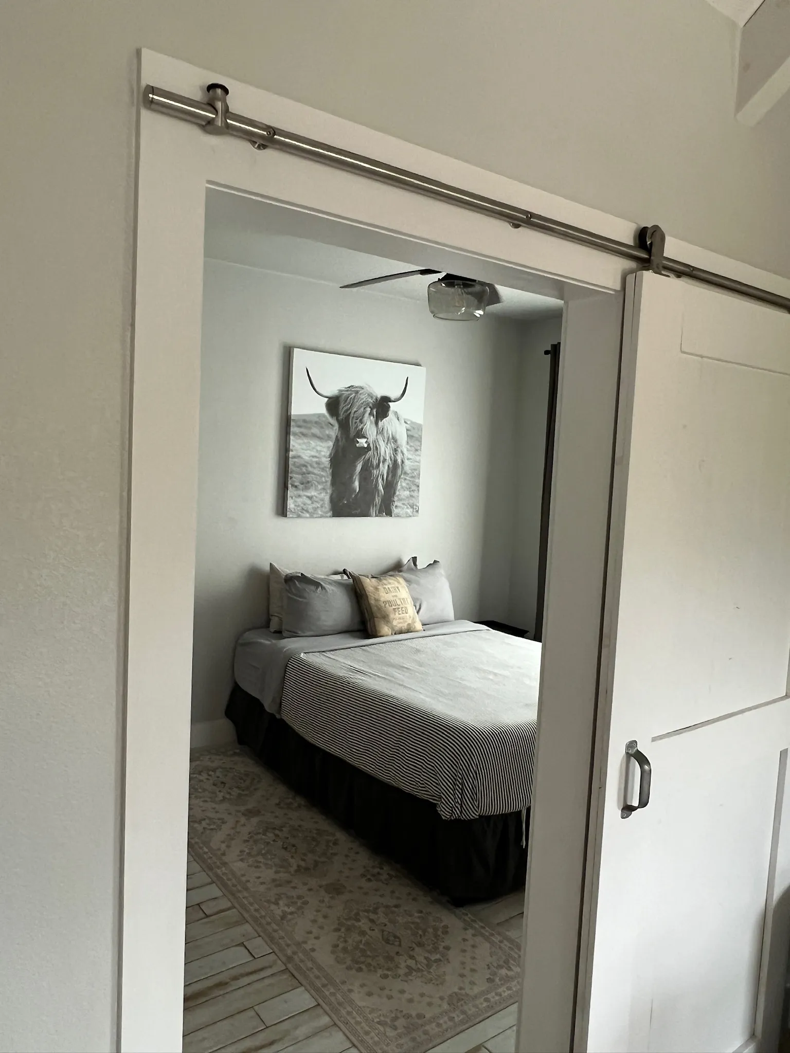 Summermoon Cottage bedroom with white barn door and Highland cattle wall art