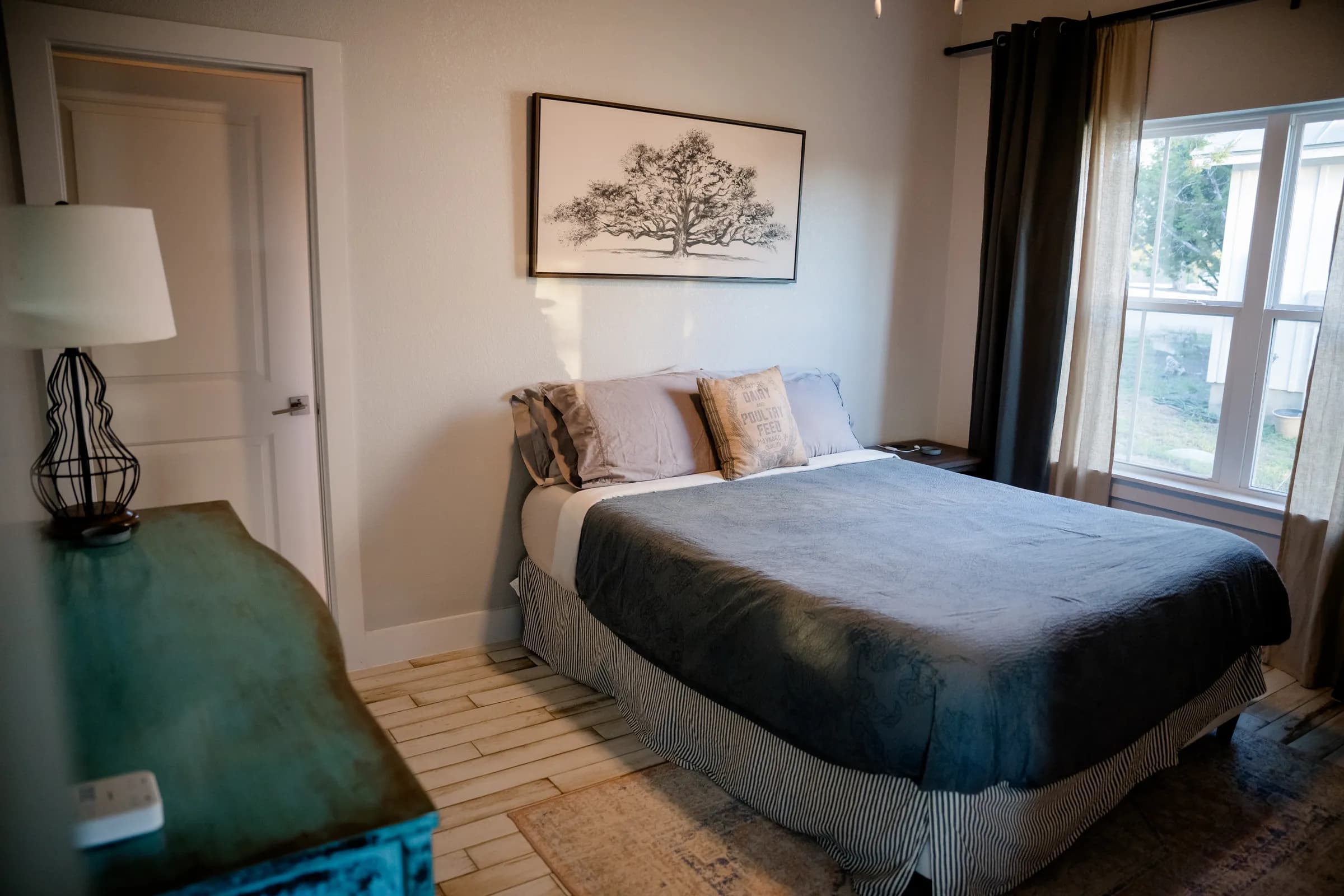 Bedroom with queen bed and oak tree artwork inside a Wayside Wimberley farmhouse cottage