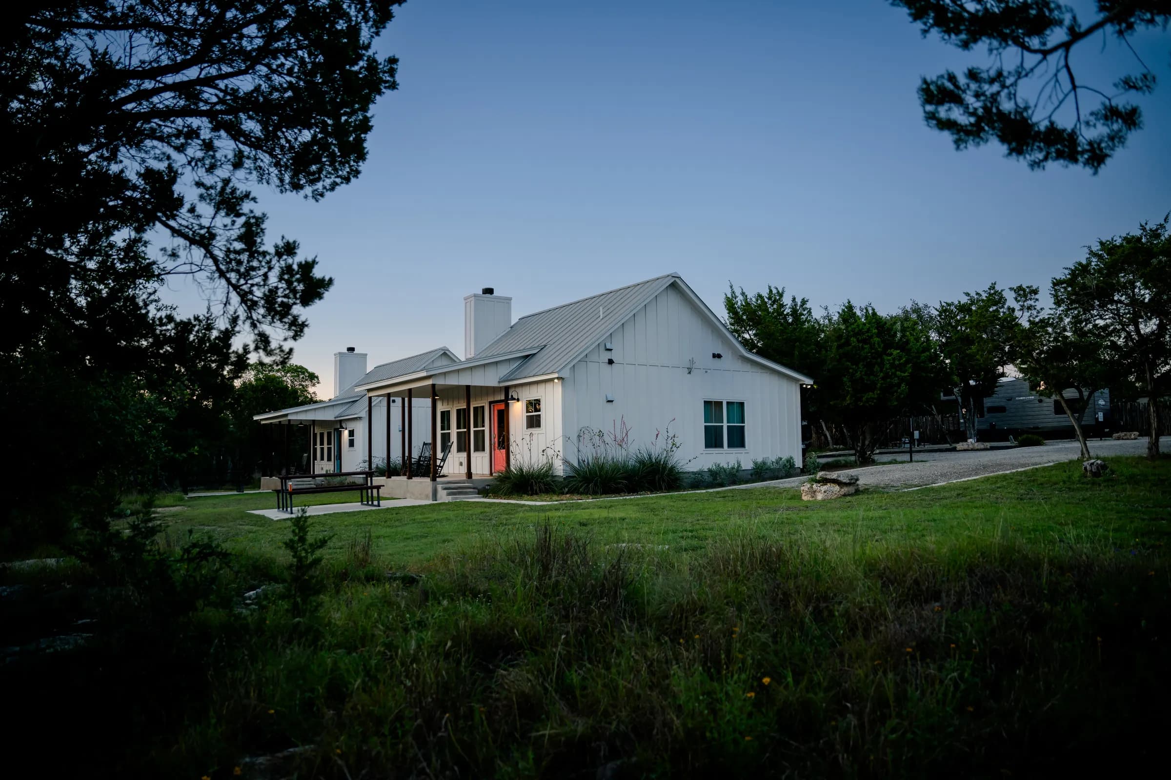 Farmhouse cottage at twilight with porch lights on at Wayside Wimberley
