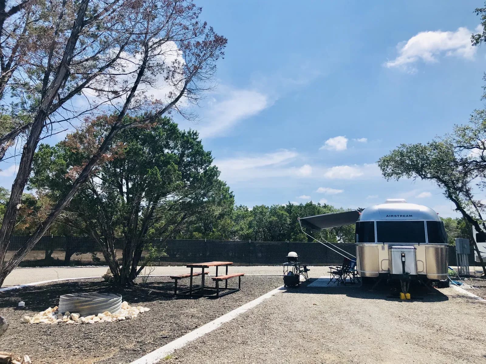Shaded RV site with Airstream under trees at Wayside Wimberley