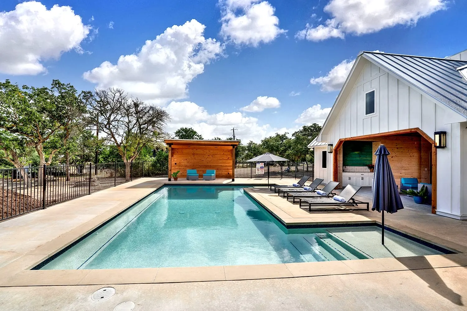Pool with white farmhouse clubhouse and outdoor seating at 660 Wayside